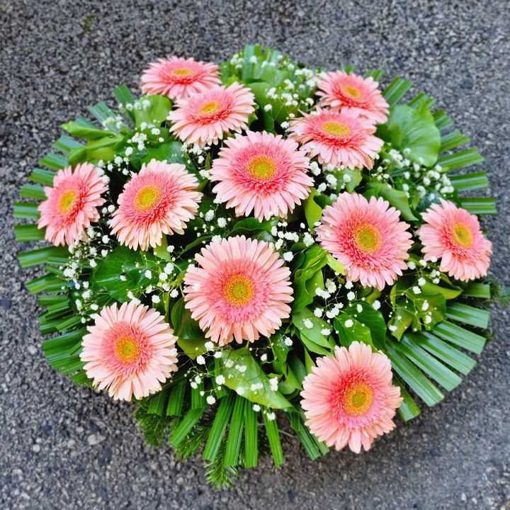 Fekvő koszorú rózsaszín gerberával és rezgővel, pálmával szegélyezve